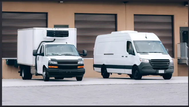 A box reefer truck and a high-roof refrigerated van parked at a warehouse
